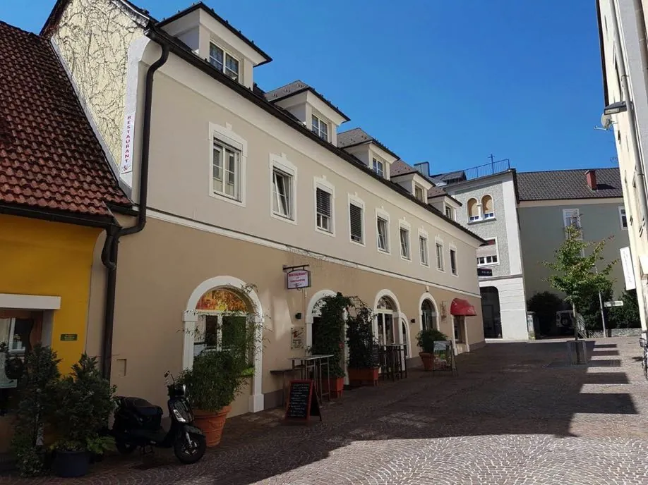 Helle Häuserzeile in einer Altstadtgasse mit Rundbogentoren und Erker