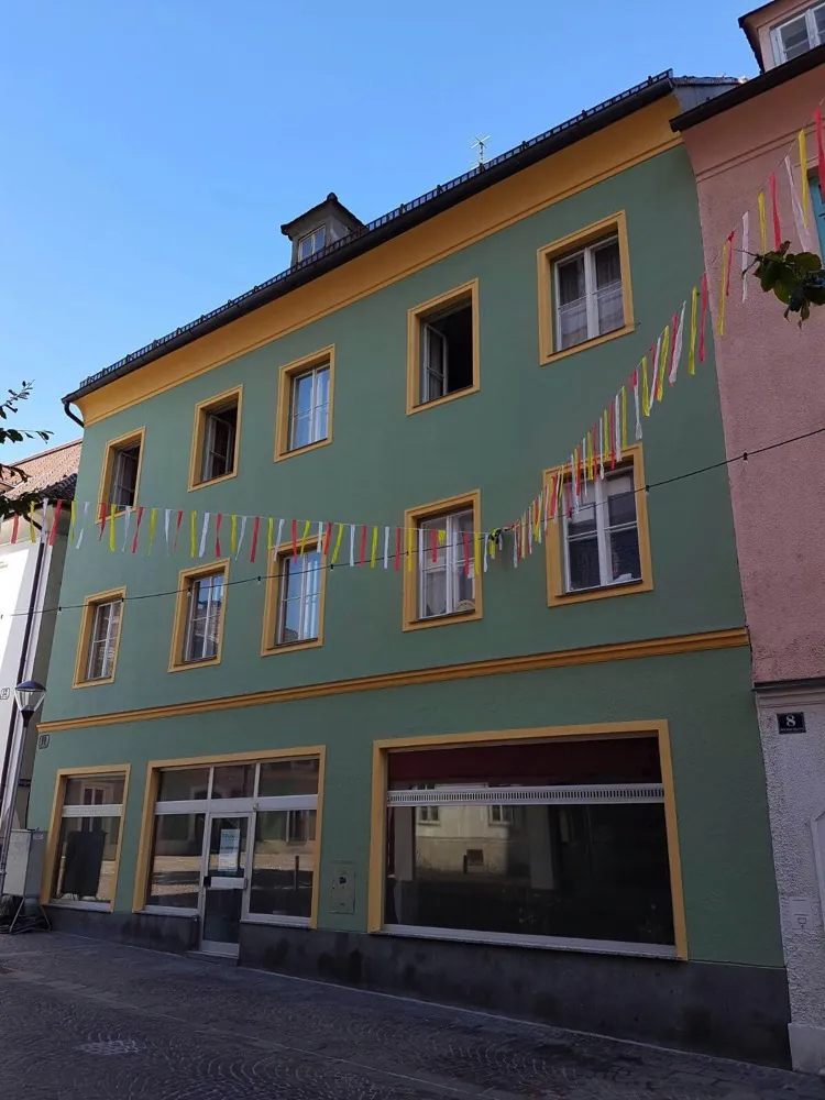 Wohnhaus mit grüner Fassade und ockerfarbenen Fensterumrahmungen