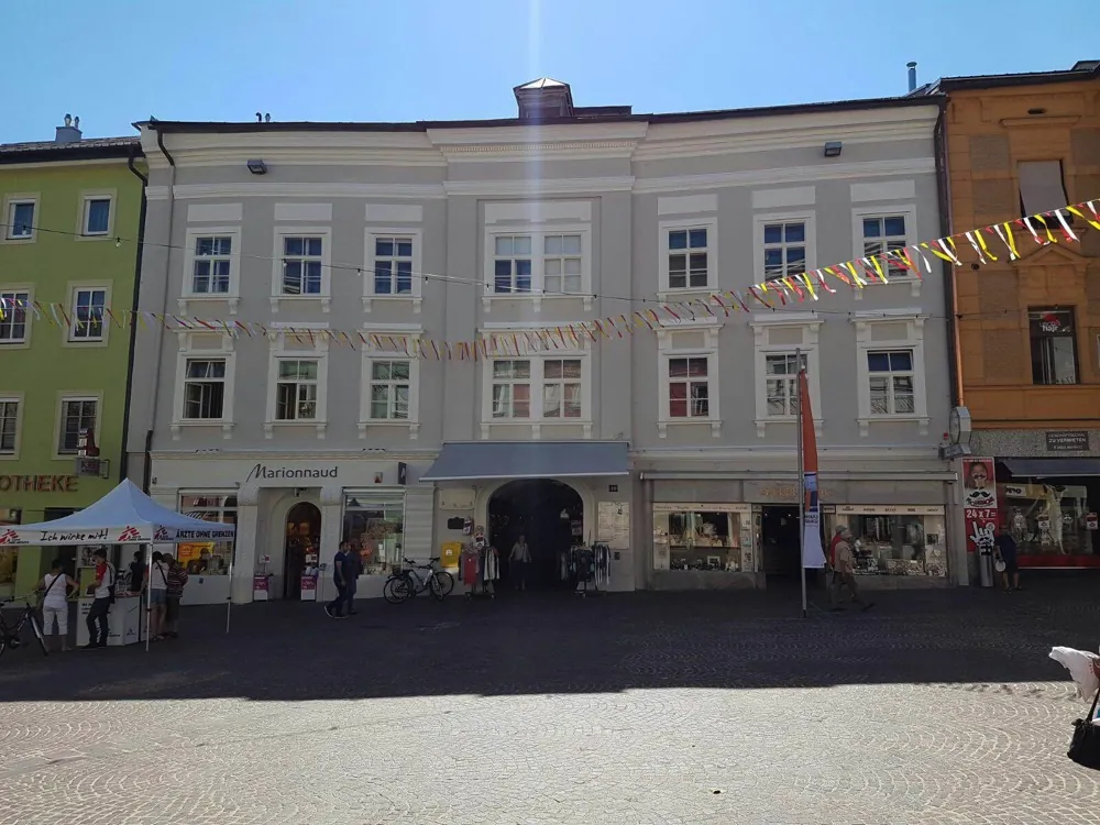 Bürgerhaus mit langer, hell gestrichener Fassade an einem Hauptplatz